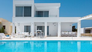 A modern two-story building with a pool in front. - Villa Constantine - Six Bedroom Villa, Sleeps 15 (Kolympia)