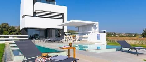 Una piscina con borde infinito, tumbonas