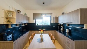 Une cuisine moderne dotée d’un îlot central, de meubles en bois et d’une fenêtre avec des stores.