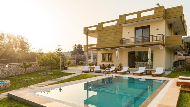 Une maison à deux étages avec une piscine, un espace extérieur aménagé et un mur en pierre.