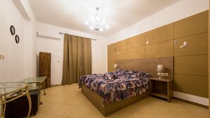 Une chambre à coucher avec un lit, une table en verre, une lampe et une armoire.