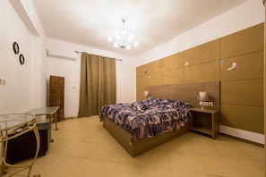 A bedroom with a bed, a glass table, a lamp, and a wardrobe.