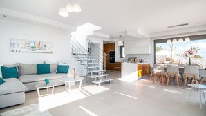 Een moderne woonkamer met een bank, salontafel en een trap die naar een keuken leidt.