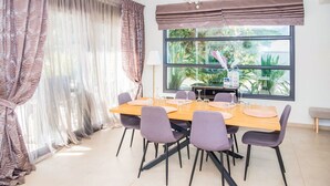 Un coin repas avec une table en bois, six chaises et une grande fenêtre donnant sur un paysage verdoyant.