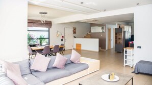 Un soggiorno moderno con divano, zona pranzo, cucina e una scala che conduce a un altro livello.