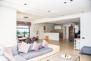 Un salon moderne comprenant un canapé, un coin repas, une cuisine et un escalier menant à un autre niveau.
