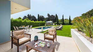 Una terrazza esterna con piscina, posti a sedere e una struttura in pietra sullo sfondo.