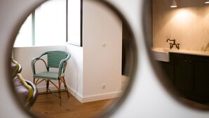 A room with a round mirror reflecting a chair, a window, and a kitchen area with a sink and cabinets. - Villa Drosoula - Two Bedroom Villa, Sleeps 4 (Fiskardo)