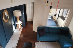A modern living room with a blue sofa, a lamp, and a mirror on the wall.
