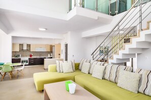 Ein modernes Apartment mit Wohnbereich, ausgestattet mit einer Sofagarnitur, einem Esstisch mit Stühlen und einer Küchenzeile mit Herd und Spüle.