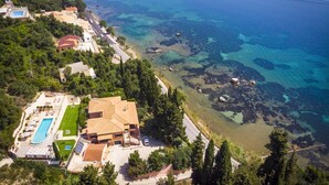 An aerial view of a coastal property with a swimming pool, a large house, and a beach. - Empress Sissi - Seven Bedroom Villa, Sleeps 14 (Gastouri)