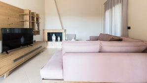 Una sala de estar moderna con un televisor de pantalla plana, un sofá rosa, un mueble de entretenimiento de madera y una chimenea.