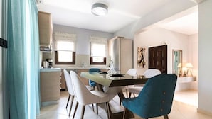 Una cocina moderna con comedor, que incluye una isla central, sillas y un refrigerador.