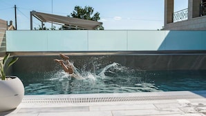 Una piscina con una persona saltando al agua, en un entorno arquitectónico moderno.