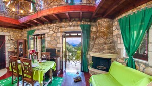 A cozy interior with a stone fireplace, a dining area, and a sofa.
