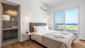 Un dormitorio con cama, mesita de noche y vista al océano.