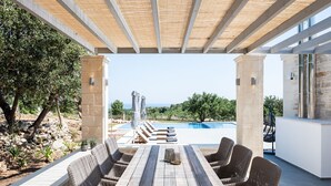 An outdoor patio with a wooden table and wicker chairs, overlooking a swimming pool and a view of the landscape. - Villa Armenoi - Three Bedroom Villa, Sleeps 8 (Apokoronos)