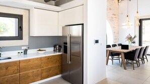 A modern kitchen with a stainless steel refrigerator, wooden cabinets, and a dining area with a wooden table and chairs. - Villa Armenoi - Three Bedroom Villa, Sleeps 8 (Apokoronos)