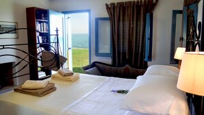 Une chambre d’hôtel avec un lit, une chaise, une bibliothèque et une vue sur la mer.
