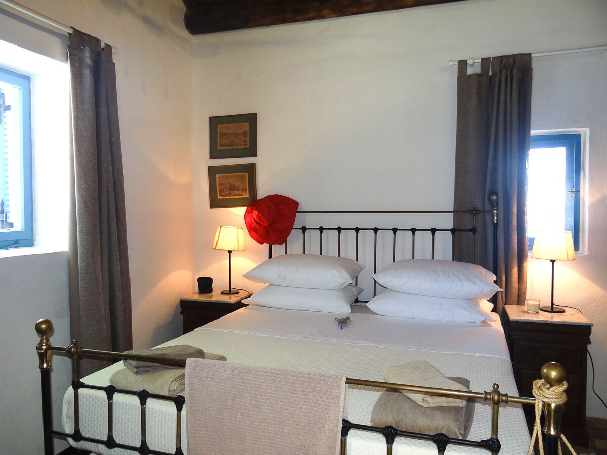 A neatly made bed with white linens, two bedside lamps, and a red rose decoration.