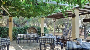 An outdoor patio with tables and chairs, covered by a pergola with grapevines. - Chapel View - One Bedroom Villa, Sleeps 2 (Ionian Islands)