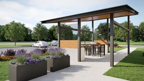 Ein überdachter Außenbereich mit modernem Design, umgeben von angelegten Blumenbeeten und einem gepflasterten Weg.
