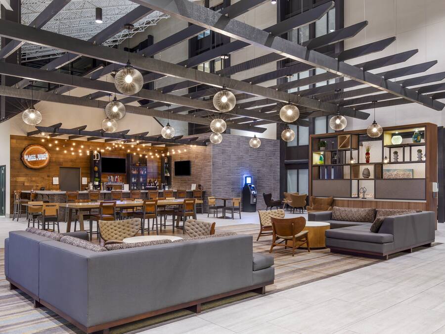 Eine großzügige Lobby mit Barbereich, Sitzgelegenheiten und einem modernen Deckenstil.