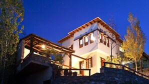 A two-story house with a stone staircase leading to the entrance, surrounded by trees and a clear night sky.
