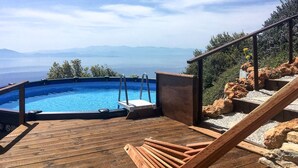 A wooden deck with a hot tub and a view of the ocean.