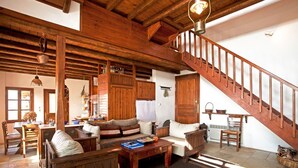 A rustic wooden interior with a staircase, wooden furniture, and a dining area.