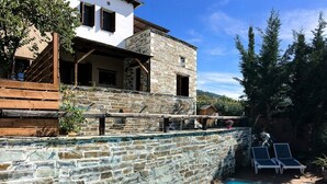 A stone-walled pool area with a clear blue pool, wooden deck, and lounge chairs. - Villa Artemida - Three Bedroom Villa, Sleeps 8 (Agios Georgios Nilias)