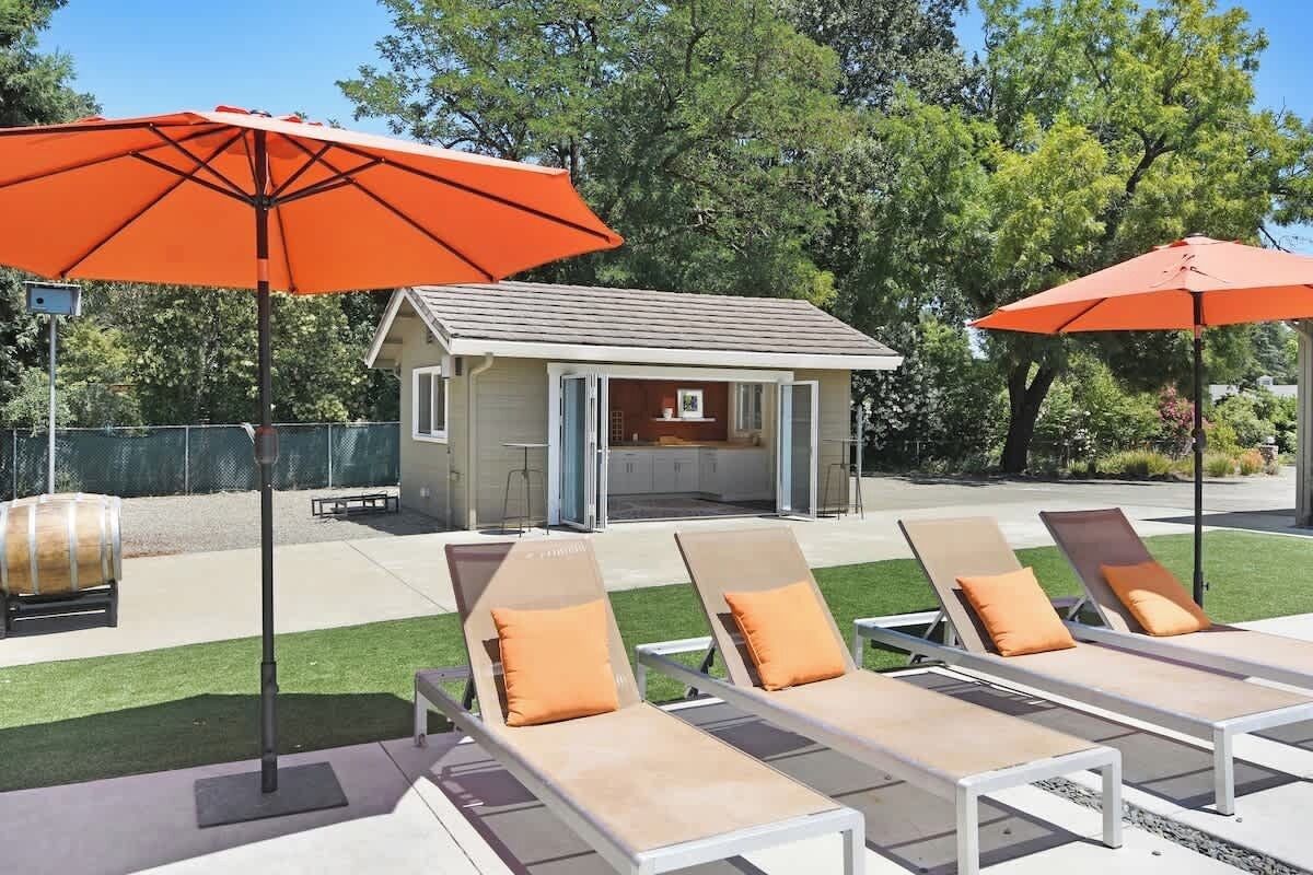 A backyard with lounge chairs and a barbecue area.