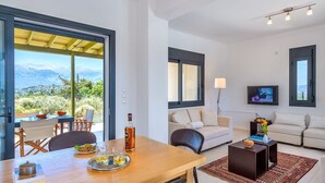 A modern living room with a sofa, coffee table, and a dining area with a table set for two.