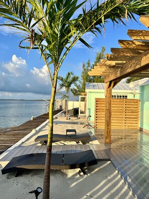 A beachside patio with a wooden deck, lounge chairs, and a pergola. - Waterfront Cottage in a Bimini oasis (Bimini)