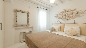 A bedroom with a bed, a wall-mounted mirror, a radiator, and a decorative wall piece.