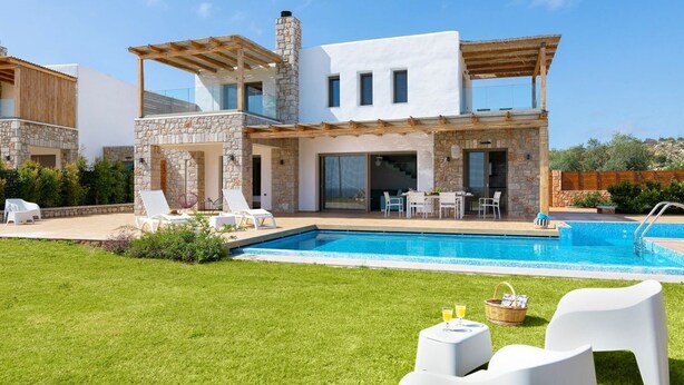 Ein modernes, zweistöckiges Haus mit Swimmingpool, Außenbereich zum Sitzen und einer Steinfassade.