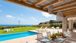 Ein Essbereich am Pool mit Meerblick, Sitzmöglichkeiten im Freien und einem Frühstücksbuffet.