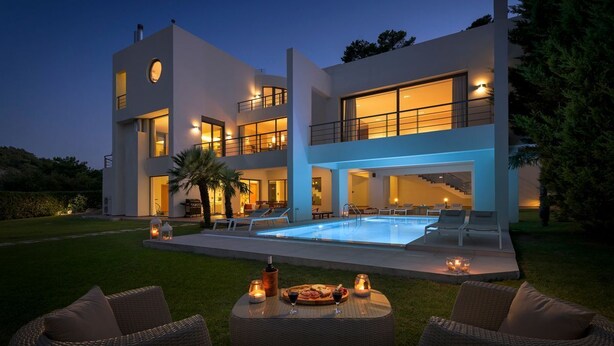 Une maison moderne à deux étages, dotée d’une piscine, d’un espace extérieur aménagé et d’un patio bien éclairé.
