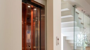 Un ascenseur moderne avec une finition métallique, une porte en verre et un panneau de commande.