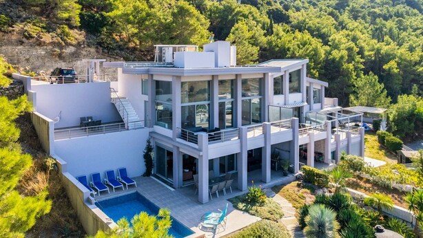 A modern two-story house with a swimming pool, outdoor seating, and a view of a forested hillside. - Villa Arthur - Four Bedroom Villa, Sleeps 8 (Rhodes)