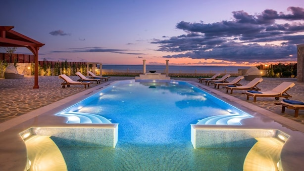 A swimming pool with lounge chairs and a pergola at dusk. - Villa Livadi - Eight Bedroom Villa, Sleeps 18 (Ferma)