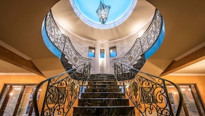 A grand staircase with ornate black metal railings, leading to a circular skylight. - Villa Livadi - Eight Bedroom Villa, Sleeps 18 (Ferma)