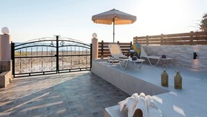 A patio with a wrought iron gate, two lounge chairs, an umbrella, and decorative lanterns. - Villa Lardos - Four Bedroom Villa, Sleeps 10 (Rhodes)