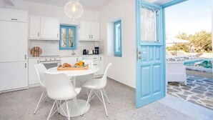 A modern kitchen with white cabinets and a blue door leading to a pool area. - Kalathos Aspro - Two Bedroom Villa, Sleeps 4 (Kalathos)