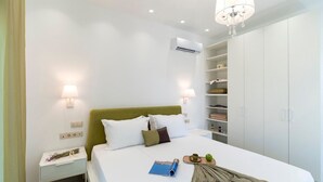 Une chambre à coucher bien aménagée, avec un lit, des tables de chevet, une armoire et un lustre.