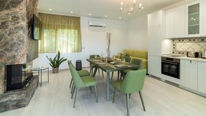 Une cuisine moderne avec des meubles blancs, un four encastré et un coin repas avec une table dressée pour quatre personnes.