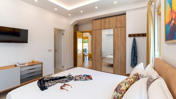 Une chambre moderne avec un lit, une table de chevet et un téléviseur fixé au mur.