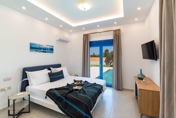 Ein modernes Hotelzimmer mit Bett, Schreibtisch, Fernseher und einem Balkon mit Blick.