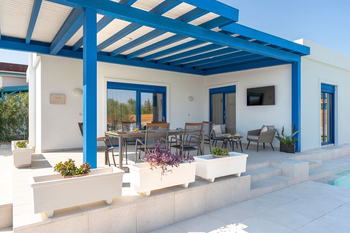 An outdoor patio with a covered seating area, a pool, and a TV mounted on the wall.