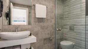 Ein modernes Badezimmer mit einem großen Waschbecken, einer Duschkabine aus Glas und einer Toilette.